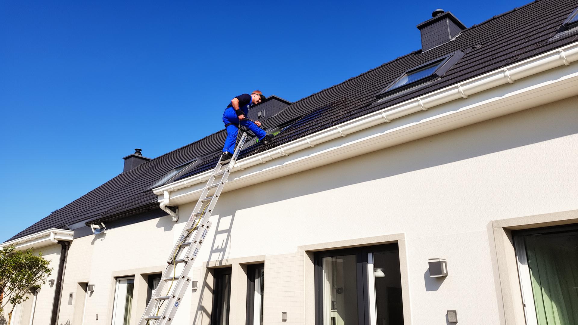 Vakman reinigt dakgoten van Belgische woning